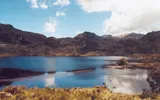 Laguna de aguas azules en el Cajas, entre montañas rocosas y pajonal dorado